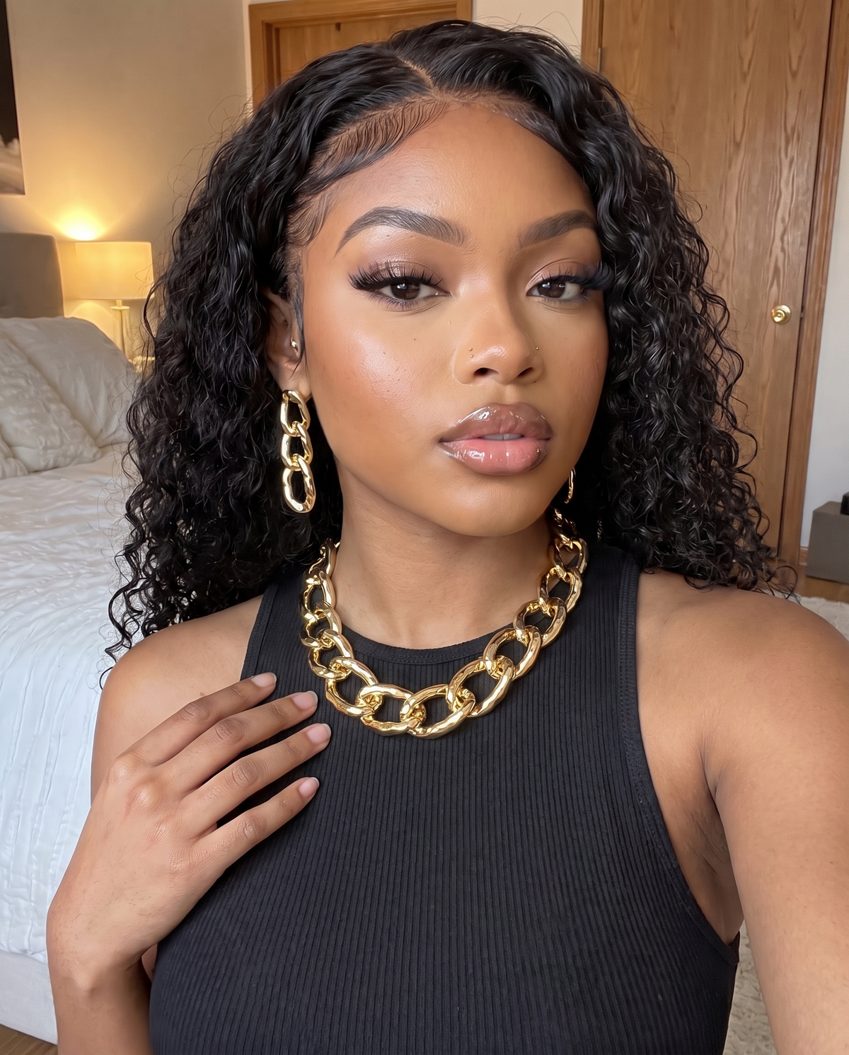 Collier grosse chaîne dorée porté au cou avec ses boucles d'oreilles, débardeur noir