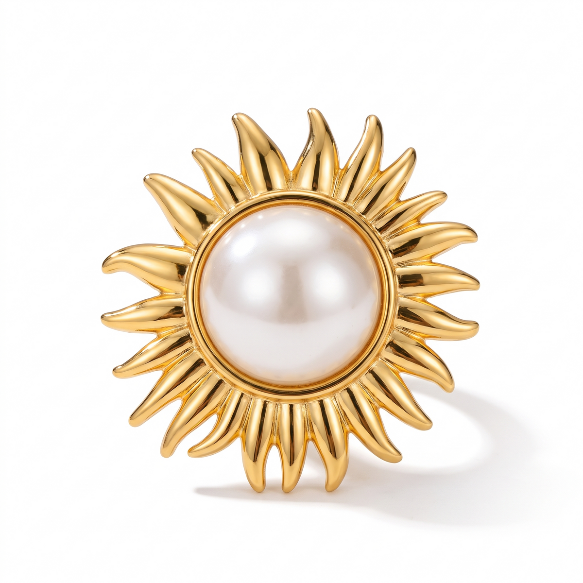 Bague dorée aux rayons ondulés autour d'une grosse perle d'imitation blanche, sur fond blanc