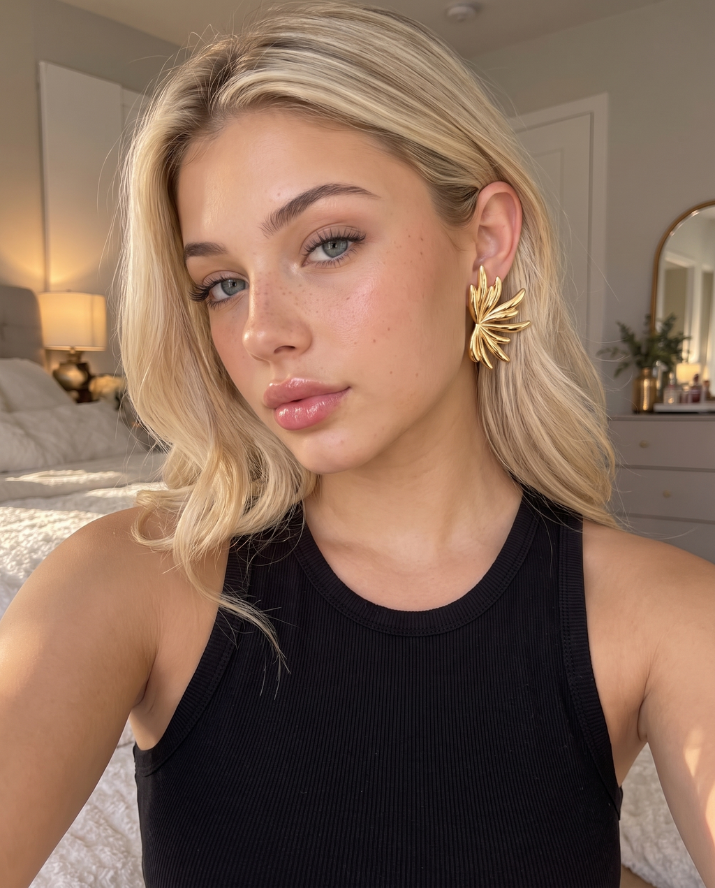 Boucle d'oreille éventail dorée portée à l'oreille, débardeur noir