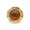 Bague dorée martelée sertie d'un gros cabochon en résine couleur ambre, sur fond blanc