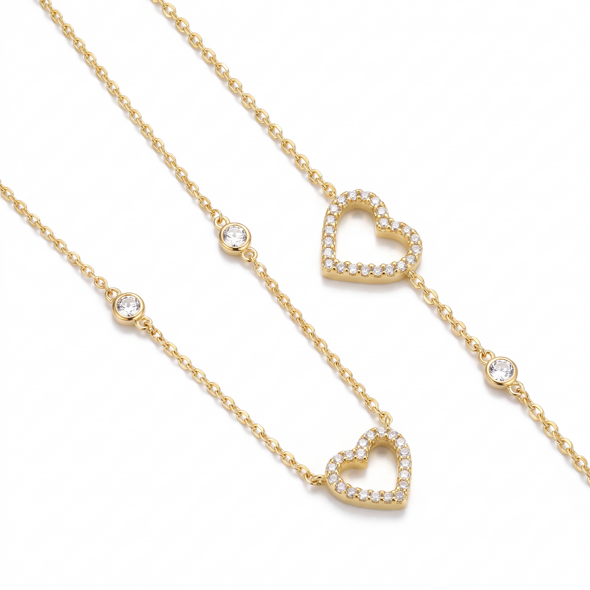 Parure dorée collier et bracelet assortis avec cœur ajouré serti de zircons, sur fond blanc