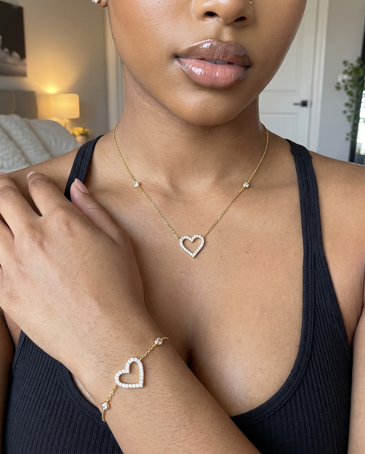 Parure cœur fin portée : collier au cou et bracelet au poignet, débardeur noir