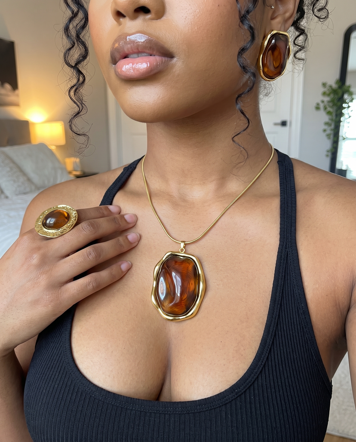 Parure couleur ambre portée : collier, boucles d'oreilles et bague, débardeur noir